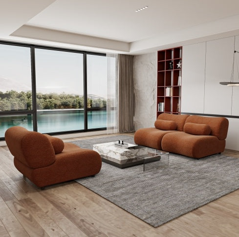 Modern living room with brown sofa and glass coffee table near large windows with a view of water.