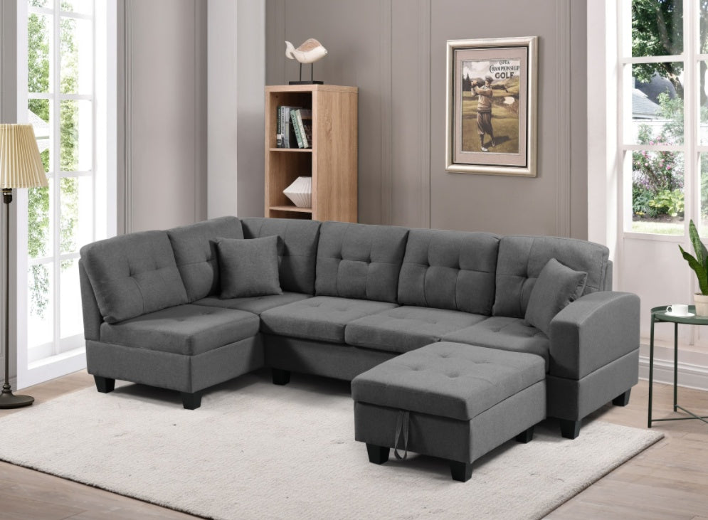 Gray sectional sofa in a living room setting with a rug and window.