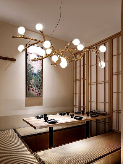 Modern chandelier with branch-like design in a room with a table and chairs.