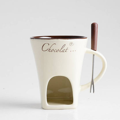 White mug with chocolate fondue insert and wooden spoon on a white background