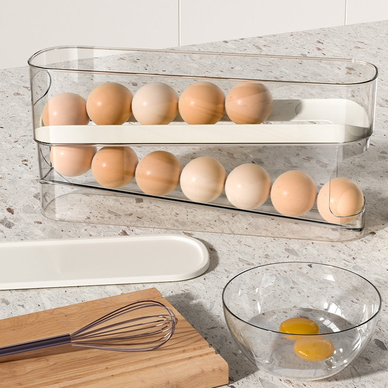Clear egg holder with eggs on a kitchen counter with a whisk and bowl.