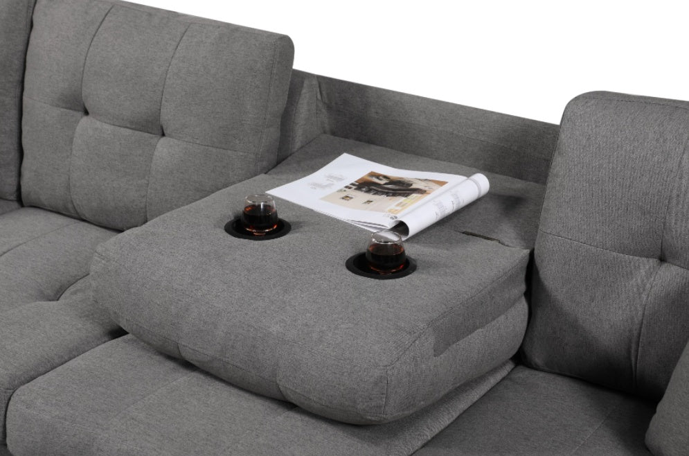 Gray sectional sofa with cup holders and a magazine on a light gray background