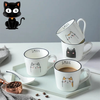 Set of white mugs with cat designs and 'SMILE' text on a light surface with coffee beans and a black cat figurine.