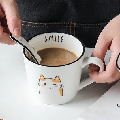 Person holding a mug with a cat design and the word 'SMILE' on a white background