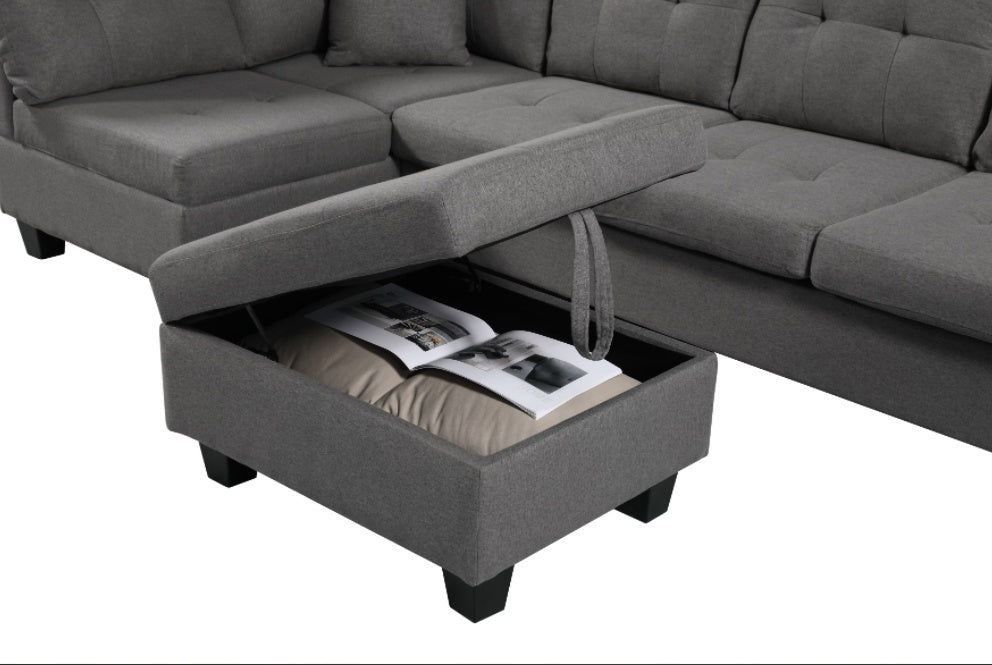 Gray sectional sofa with an open storage drawer containing books and a bag.