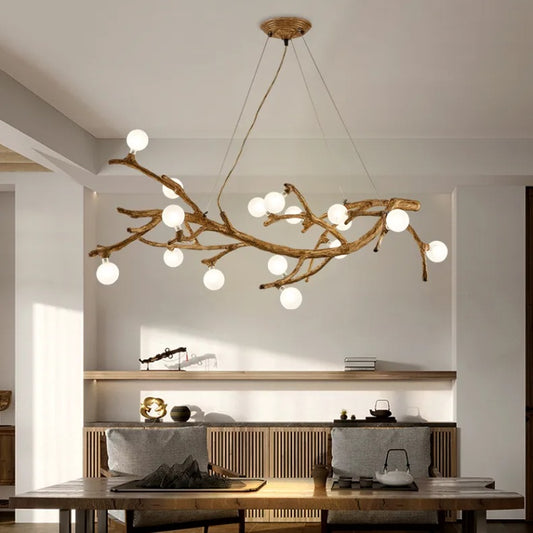 Modern chandelier with branch-like design in a room with a dining table and chairs.